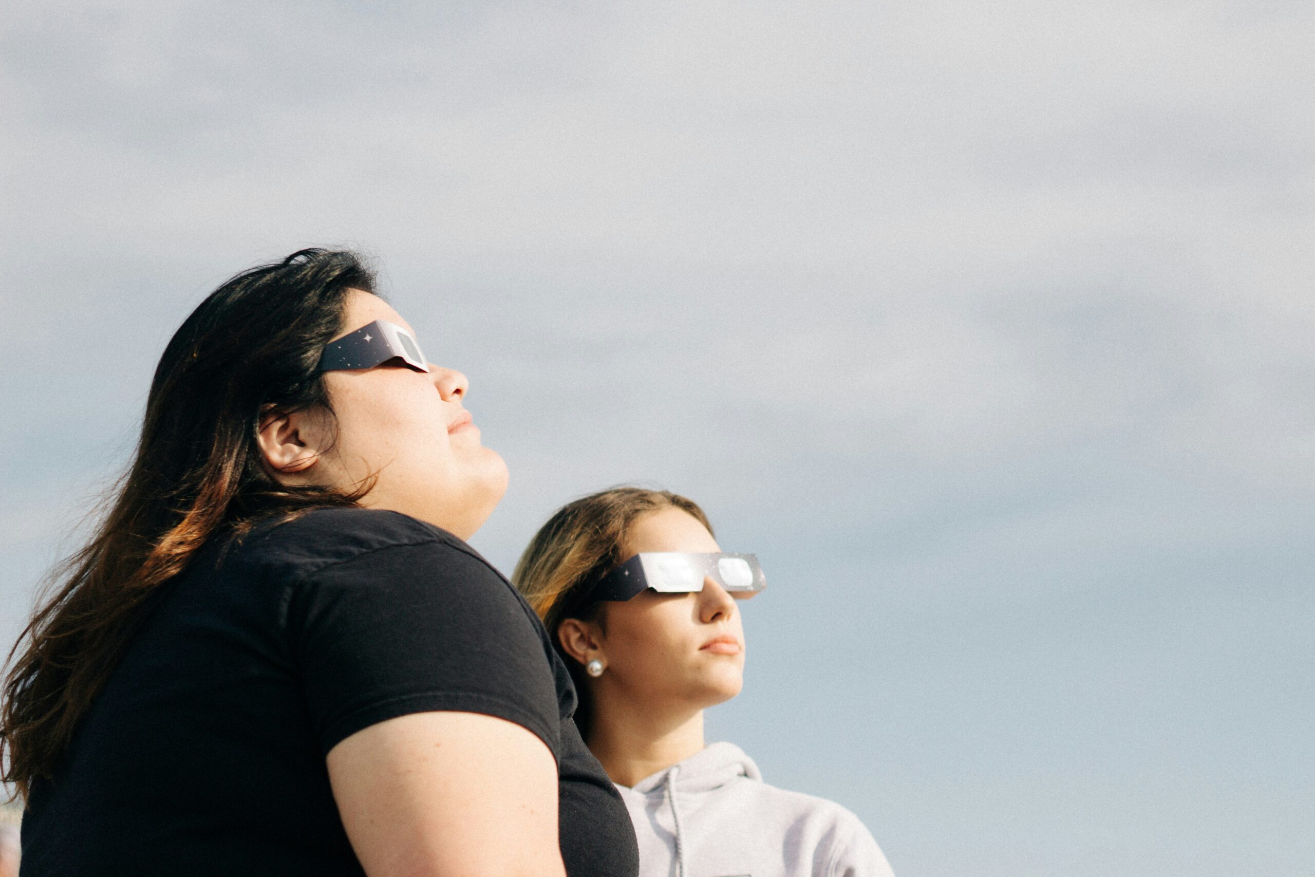 Two women wearing eclipse glasses watching the 2024 solar eclipse in Austin, Texas.
