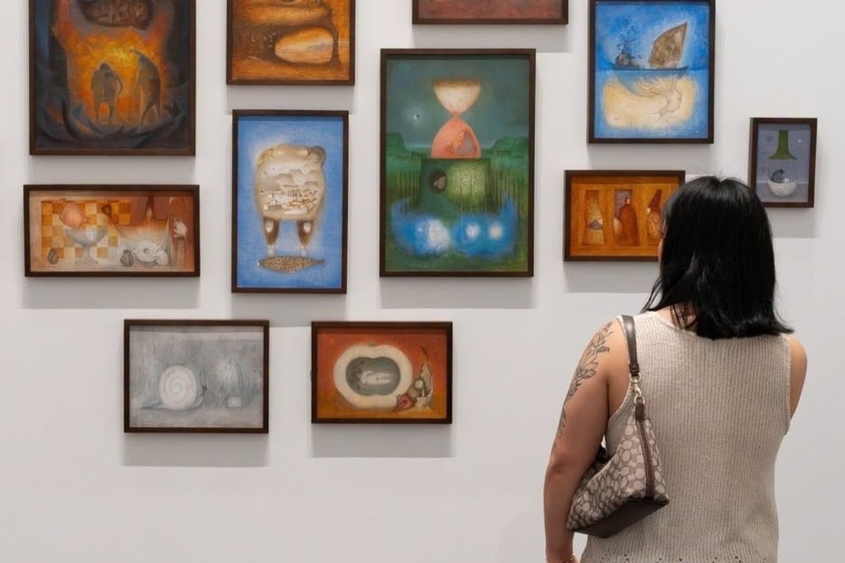 A visitor admiring paintings by Mario Rangel Sánchez on the wall at the Blanton Museum of Art in Austin, Texas, a top indoor activity recommended by the Heywood Hotel.