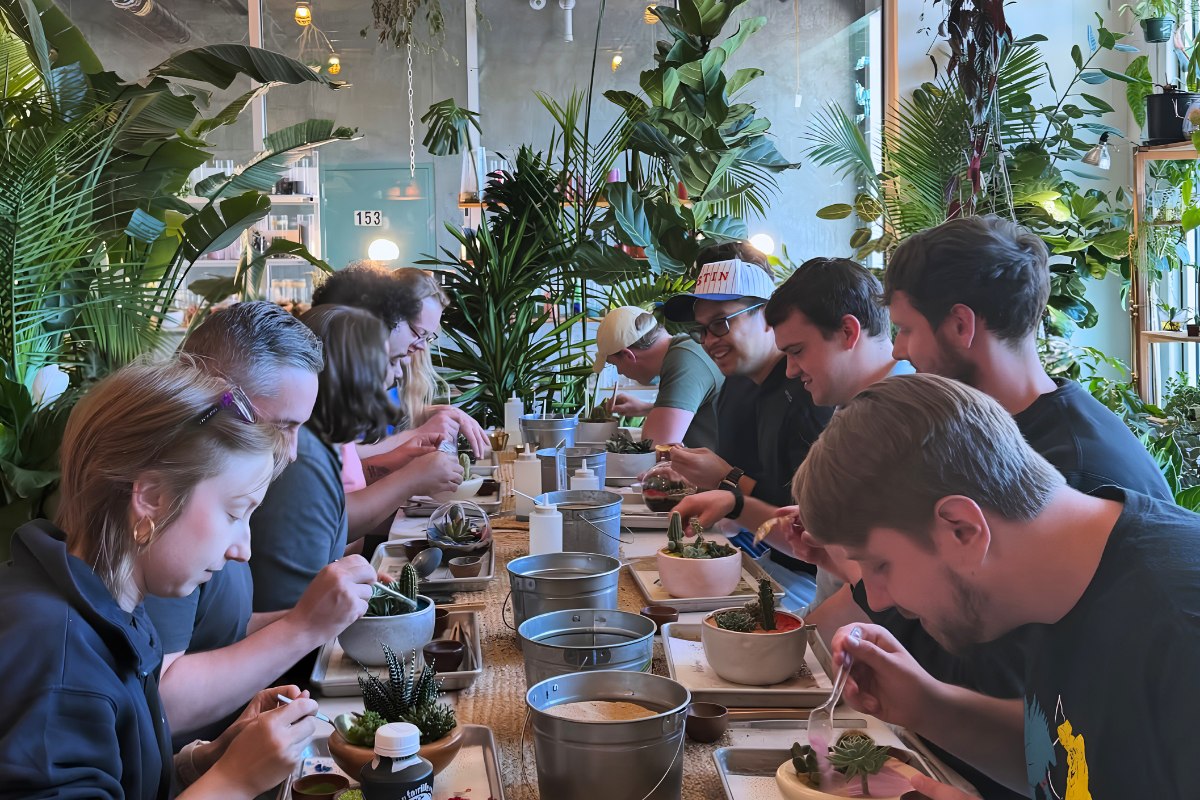 A group of guests building terrariums at a Plant Party workshop in East Austin, surrounded by tropical plants, one of the best crafty things to do indoors in Austin.