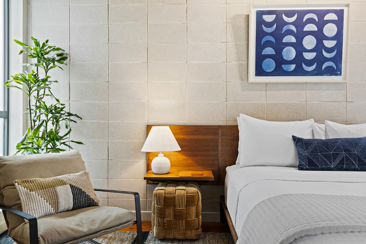 Room 3, Courtyard Queen Room at the Heywood Hotel in East Austin, with a queen bed, walnut headboard, moon phases artwork above the bed, and a stone feature wall.